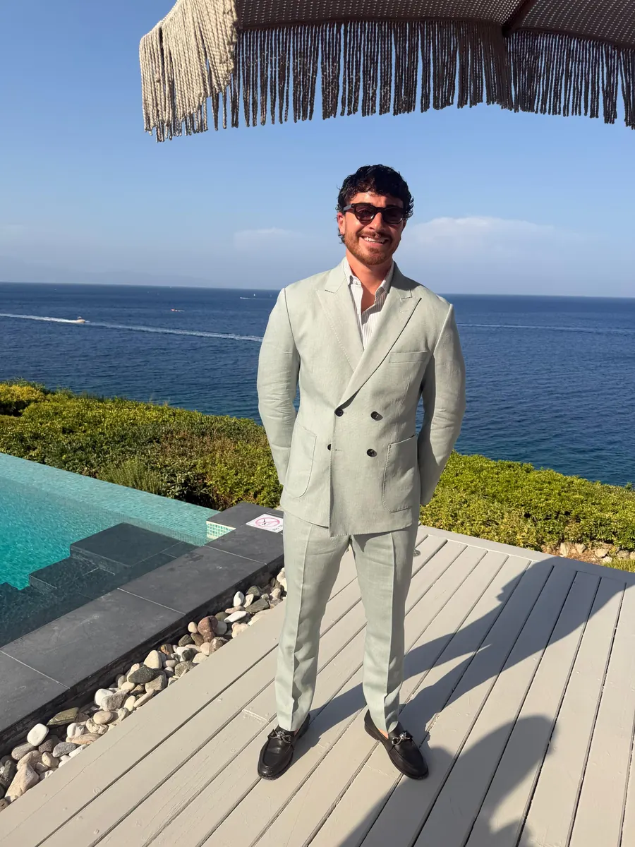Cliente con traje cruzado de lino verde salvia a medida junto al mar