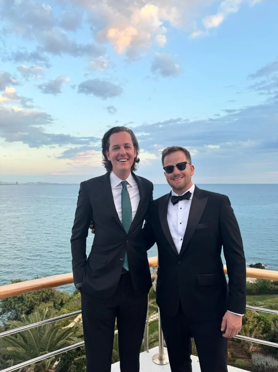 Dos clientes con traje negro y esmoquin a medida junto al mar